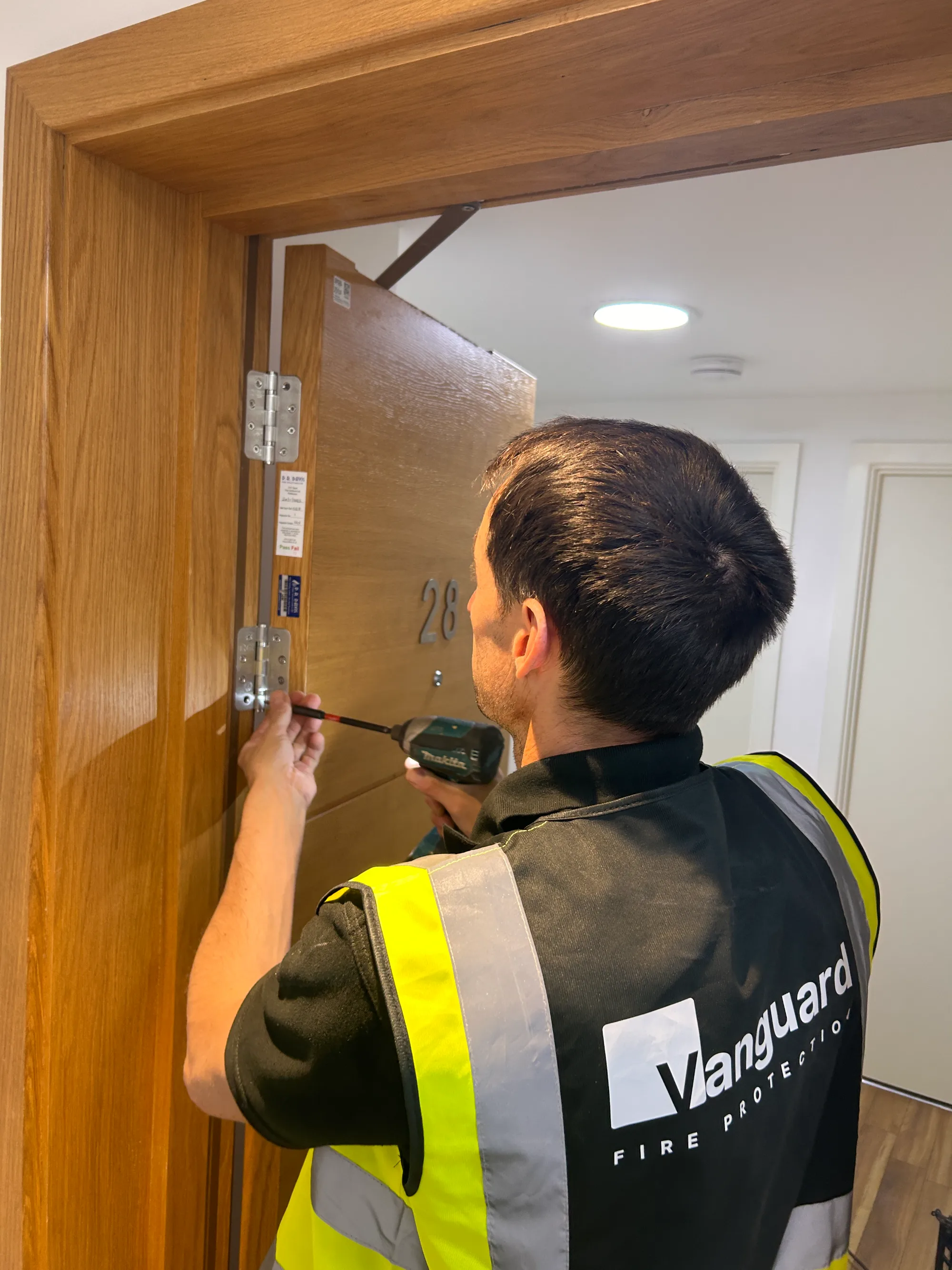 Vanguard engineer carrying out maintenance on a fire door