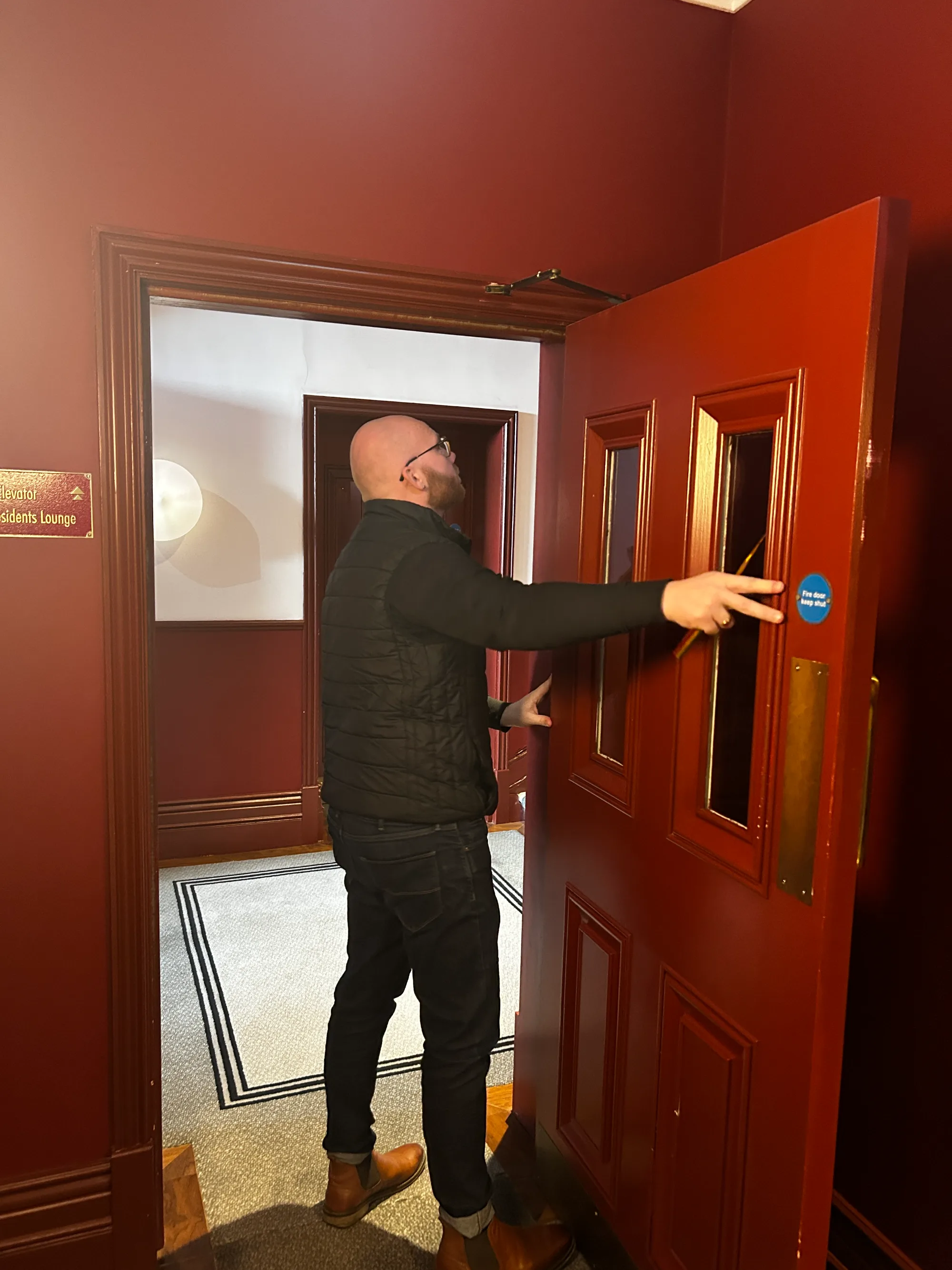 Vanguard engineer inspecting the hinges of a timber fire door